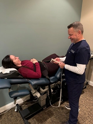 Dr. Andrew Knecht interacting with a patient on an adjustable treatment table.