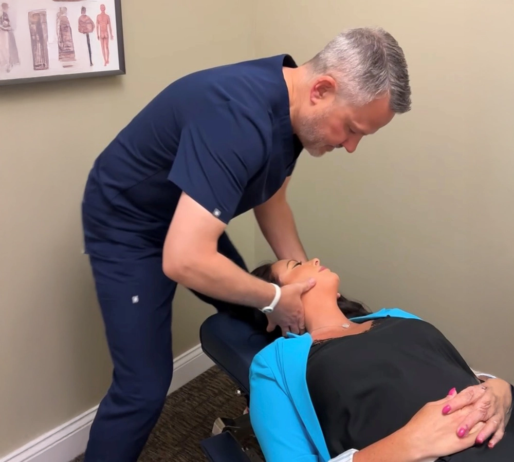 Dr. Andrew Knecht performing a neck adjustment on a patient lying on a treatment table.