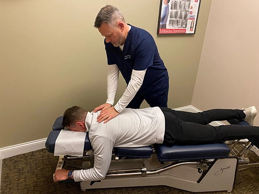 Dr. Andrew Knecht adjusting a patient lying face down on an adjustment table.